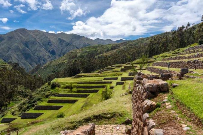 Panoramic view of ancient Inca terraces along the Inca Trail Trek surrounded by green mountains.